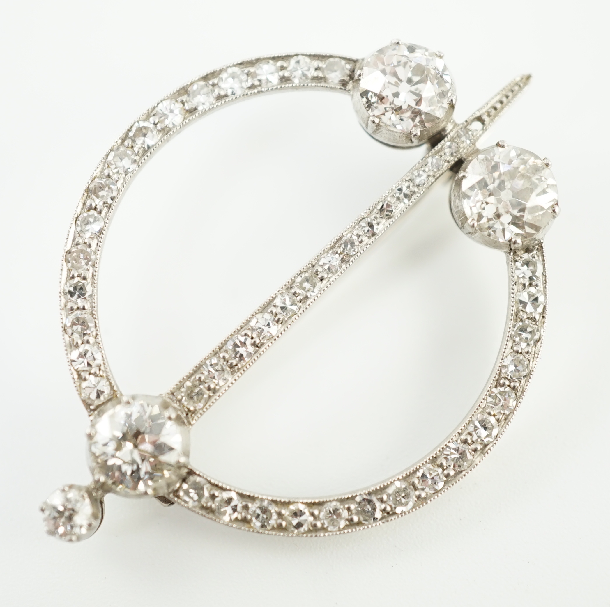 A 1920's platinum or white gold, diamond cluster set openwork 'dagger and circle' brooch